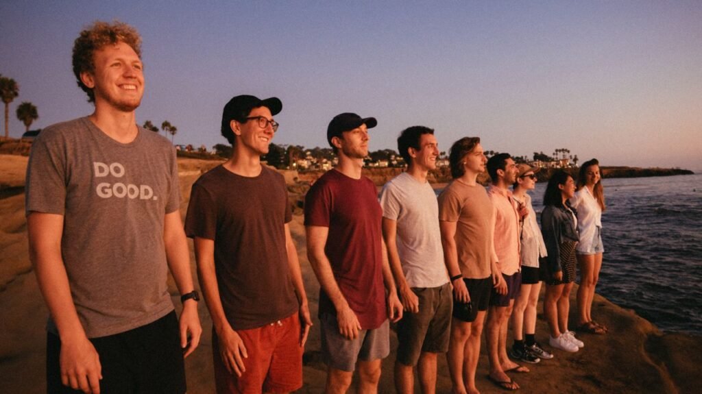 A group of friends smiling at the sunset by the rocky seaside.